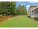 Large backyard featuring a screened porch, lush lawn, and mature trees along a wooden fence at 1304 Swallows Walk, Grayson, GA 30017