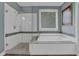 A bathroom features a glass shower and a soaking tub with tile surround, along with a single window at 1304 Swallows Walk, Grayson, GA 30017