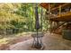 A shaded back patio features an outdoor dining set, stairs to a deck and a wooded view at 2849 Crescendo Dr, Atlanta, GA 30318