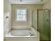 Spacious bathroom featuring a soaking tub, glass-enclosed shower, and tiled walls at 4970 Clubgreen Smt, Stone Mountain, GA 30088