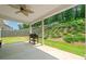 Covered back patio with a grill, ceiling fan and views of the grassy, landscaped backyard at 151 Rolling Hills Pl, Canton, GA 30114