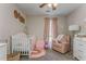 Charming Bedroom features a crib, pink accents, and a cozy reading corner with natural light at 3288 Owens Meadow Ln, Kennesaw, GA 30152