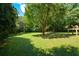 Large backyard with mature trees, green grass, and a raised deck with seating at 2116 Strasburg Ct, Atlanta, GA 30338
