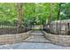Stone retaining wall topped with black metal fencing overlooks the tiered backyard at 5285 Bannergate Dr, Johns Creek, GA 30022