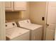 Laundry room with white washer and dryer, cabinets, and a door, designed for efficiency and convenience at 1003 River Plantation Dr, Woodstock, GA 30188