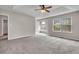Light-filled main bedroom with carpet, a ceiling fan, and ensuite bath with a large window at 1138 School Side Dr, Lithonia, GA 30058
