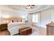 Bright main bedroom featuring tray ceilings, ceiling fan, neutral colors, wood floors, and a decorative trunk at the foot of the bed at 3290 Cherry Oak Ln, Cumming, GA 30041