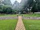 A lush green backyard with a brick path leading to a swing set, bordered by stone walls at 3532 W Hampton Nw Dr, Marietta, GA 30064