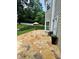 A beautiful stone patio beside the home with an umbrella and meticulously maintained landscaping at 3532 W Hampton Nw Dr, Marietta, GA 30064