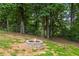 Stone fire pit in fenced backyard featuring mature trees, ideal for outdoor gatherings at 2990 Cove Crossing Dr, Lawrenceville, GA 30045