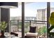 Balcony view showing city skyline and trees, with outdoor seating and throw pillows at 620 Peachtree Ne St # 1206, Atlanta, GA 30308