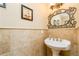 Powder room featuring travertine walls and an ornate mirror at 271 Double Gate Ct, Sugar Hill, GA 30518