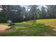 Spacious backyard featuring a grassy lawn, mature trees, an outdoor grill and a fire pit at 4162 Riverdale Dr, Snellville, GA 30039
