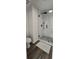 Modern white tiled shower with black hardware and wood look tile flooring at 4162 Riverdale Dr, Snellville, GA 30039