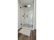 Modern white tiled shower with black hardware and wood look tile flooring at 4162 Riverdale Dr, Snellville, GA 30039