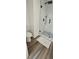 Modern white tiled shower with black hardware and wood look tile flooring at 4162 Riverdale Dr, Snellville, GA 30039