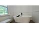 Elegant bathroom featuring a freestanding tub, textured wall tiles, and a bright window at 4162 Riverdale Dr, Snellville, GA 30039