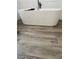Modern white soaker bathtub with black fixtures and wood look tile flooring at 4162 Riverdale Dr, Snellville, GA 30039