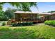 Backyard view of a screened-in porch with wooden deck and stairs, surrounded by green grass and mature trees at 81 Laurie Ct, Hiram, GA 30141