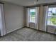 Bedroom featuring two windows with white and black curtains and neutral carpet at 105 Marchmont Dr, Locust Grove, GA 30248