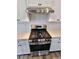 A close view of a stainless-steel gas range with white cabinets and white subway tile backsplash at 105 Marchmont Dr, Locust Grove, GA 30248