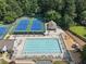 Aerial shot showcasing a large community pool, tennis courts, and playground in a wooded setting at 14 Augusta Way, Hiram, GA 30141