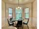 Bright breakfast nook features a round table, chandelier, and three windows overlooking the backyard at 5783 Poppy Tree Ln, Tucker, GA 30084