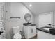 Bathroom featuring gray walls, wood look flooring, toilet, round mirror, white cabinet and black countertop at 1174 Princess Sw Ave, Atlanta, GA 30310