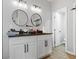 Bathroom featuring dual vanity, round mirrors and modern fixtures, with white cabinets and wood-look flooring at 1174 Princess Sw Ave, Atlanta, GA 30310