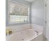 Relaxing bathtub beneath a sunny window in this bathroom at 3589 Garden Manor Dr, Loganville, GA 30052