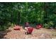 Secluded fire pit area with red Adirondack chairs nestled in a lush, wooded backyard at 3990 Wesley Chapel Rd, Marietta, GA 30062