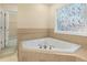 Bathroom featuring a soaking tub with mosaic window, tile detail, and an adjacent doorway at 3460 Drayton Manor Run, Lawrenceville, GA 30046