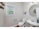 Cozy half bathroom with a decorative round mirror, pedestal sink, and a window that allows natural light at 1120 Bagwell Dr, Kennesaw, GA 30152