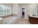 Bathroom showcases a corner soaking tub, large window, and open access to a walk-in closet with custom shelving at 1120 Bagwell Dr, Kennesaw, GA 30152