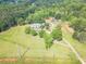 Areal view of lush property featuring a home, barn and expansive lawns lined with trees at 2229 S Van Wert S Rd, Villa Rica, GA 30180