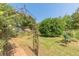 Charming backyard featuring garden plots, mature trees, and an ornate archway at 2229 S Van Wert S Rd, Villa Rica, GA 30180