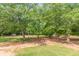 Spacious backyard with mature trees and a chicken coop in the distance at 2229 S Van Wert S Rd, Villa Rica, GA 30180