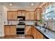 Kitchen features wood cabinets, stainless steel appliances and black countertops with a sink beneath a window at 2837 Peachstone Ct, Lawrenceville, GA 30043
