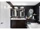 Well-lit bathroom with dual sinks, framed mirrors, and a combination tub-shower unit at 7628 Summer Berry Ln, Lithonia, GA 30038