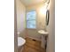 Small bathroom with hardwood floors, pedestal sink, and a window providing natural light at 2104 Meadow Peak Rd, Duluth, GA 30097