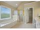 Bright bathroom with a soaking tub under a window and a glass-enclosed shower with gold trim at 2802 Arabian Ne Trl, Marietta, GA 30062