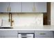 Close-up of modern kitchen featuring white countertops, tile backsplash, and grey cabinets with gold accents at 20 Marietta Nw St # 15D, Atlanta, GA 30303