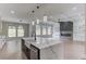 Well-lit kitchen with dark fixtures, white cabinetry, and a large island facing large windows and an open-concept living space at 37 Deer Canyon Dr, Auburn, GA 30011