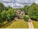 Aerial view of a brick home surrounded by mature trees and a long driveway at 9035 Brixham Ct, Suwanee, GA 30024