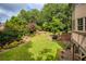 Manicured backyard with lush lawn, mature trees, and stone retaining walls for landscaping at 9035 Brixham Ct, Suwanee, GA 30024