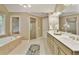 Bathroom with double vanity, soaking tub, and a glass-enclosed shower featuring tiled accents at 9035 Brixham Ct, Suwanee, GA 30024