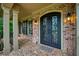 Elegant glass front doors framed by brick columns and sconce lighting at 9035 Brixham Ct, Suwanee, GA 30024
