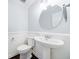 Well-lit bathroom featuring a pedestal sink, oval mirror, and decorative wainscoting at 13 Ivy Ne Sq, Atlanta, GA 30342
