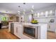 Island kitchen with white cabinets, stainless steel appliances, gold hardware, and modern lighting at 4395 Woodland Brook Se Dr, Atlanta, GA 30339