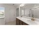 Bathroom featuring double sinks, wood cabinets, quartz counters and a walk-in shower at 61 N Auburn Landing Pl, Auburn, GA 30011